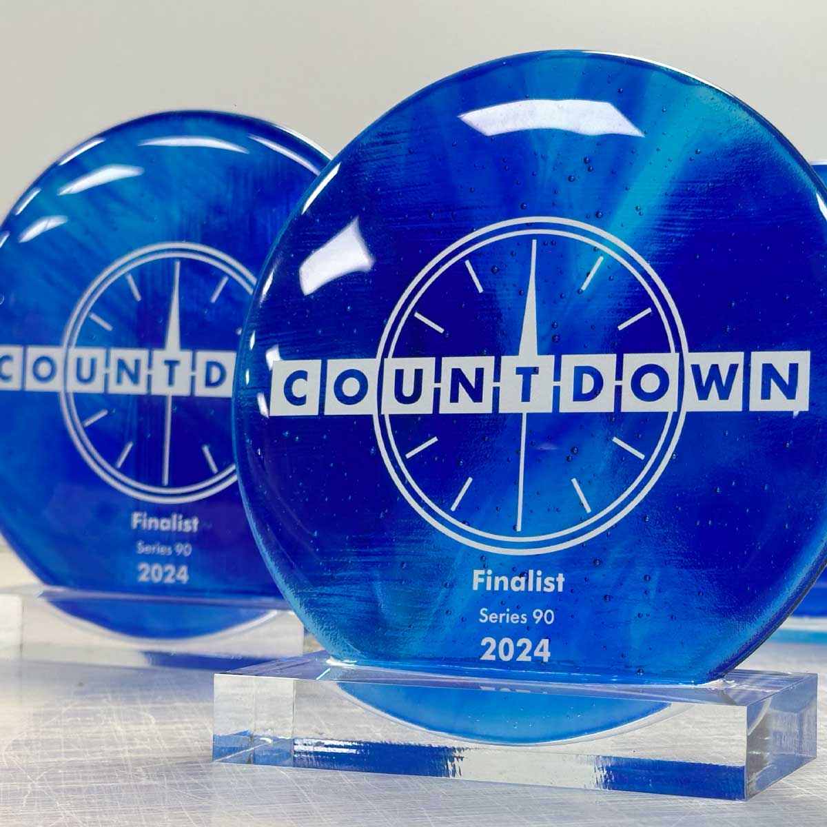 Countdown Series 90 finalist trophy – blue recycled glass with acrylic base and printed clockface logo