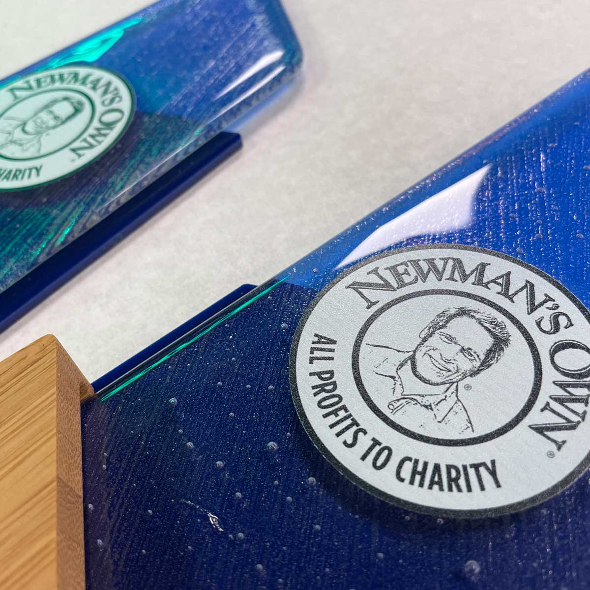 Newman’s Own charity award with deep blue fused glass and bamboo base – featuring engraved logo of Paul Newman