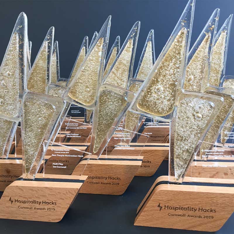 Lightning bolt Hospitality Hacks Cornwall Award trophies with gold-filled acrylic and timber bases for winners