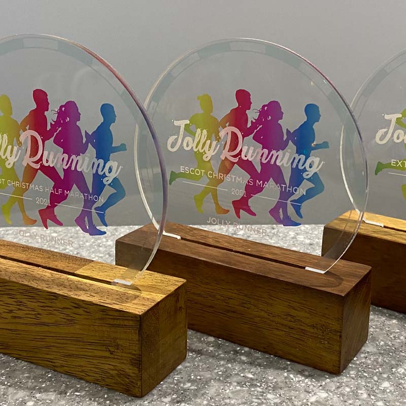 Jolly Running award with rainbow runner silhouettes on acrylic disc and timber base – custom fun run trophy
