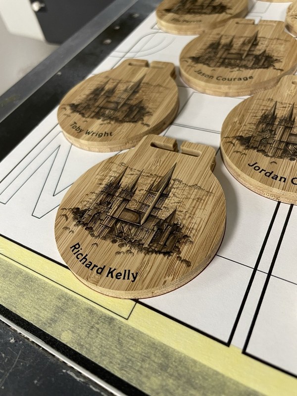 Bamboo medal reverses engraved with a cathedral illustration and individual recipient names