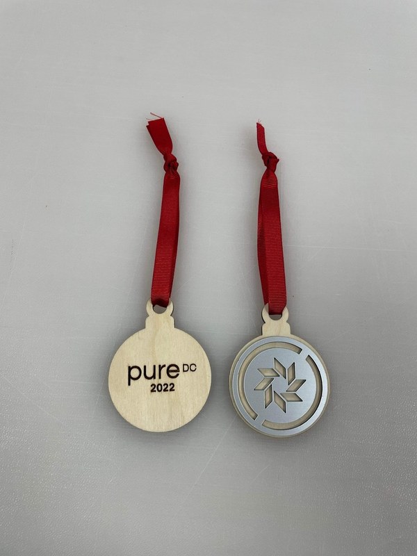 Pure DC custom wooden medals with red ribbons, showing an engraved logo and a layered geometric design