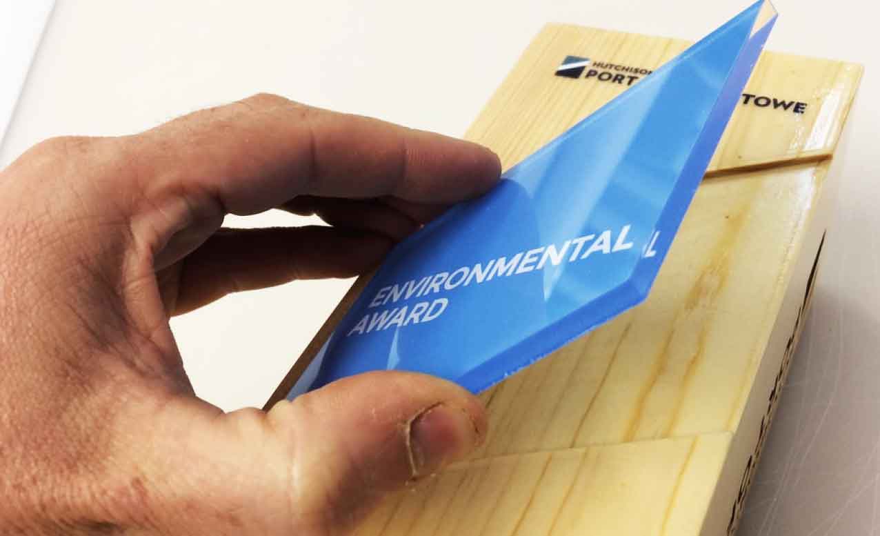 Assembling a blue environmental award on a wooden base